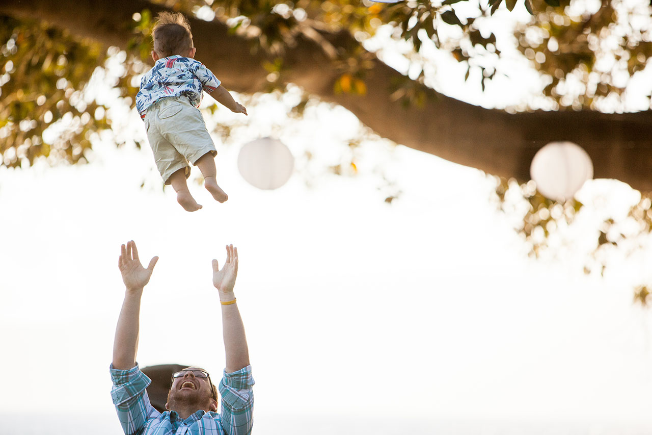baby boy being tossed in the air at a wedding reception at olowalu plantation house in maui