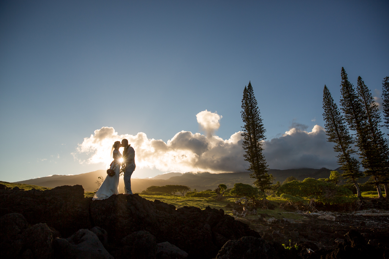 A wedding couple kiss as the sun shines through them in Hana Maui.