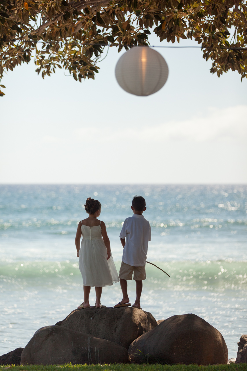 @ young wedding guests stand on a rock staring at the ocean at Olowalu Maui.