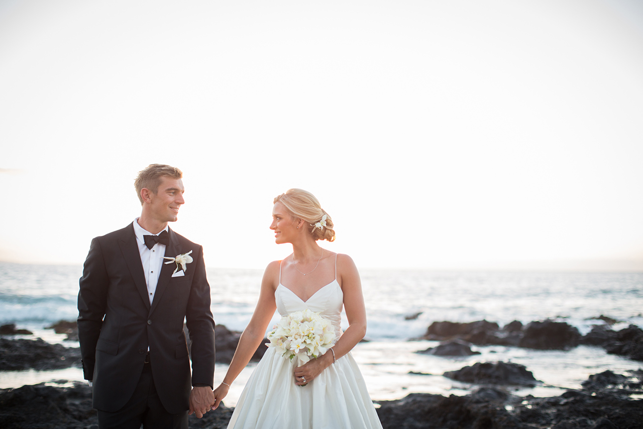 Photo of a wedding couple holding hands looking at each other on the seaside in Maui.