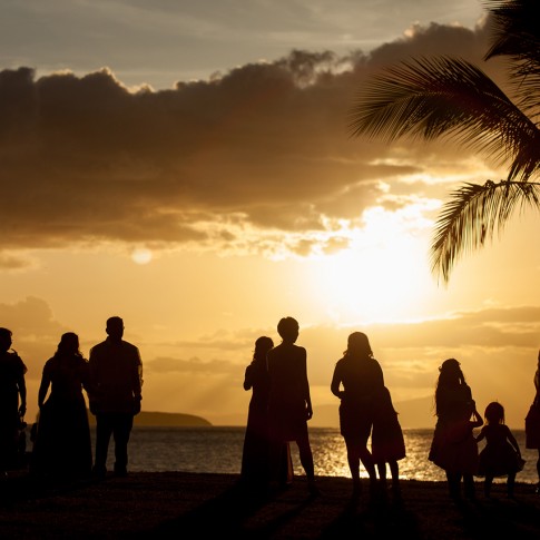 Silhouetted wedding guests enjoy the sunset view at a destination wedding in Makena Maui.