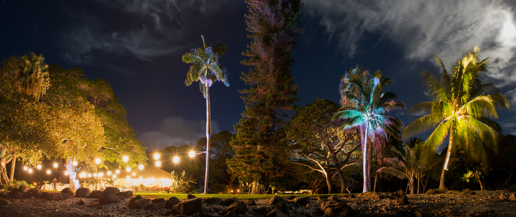 A Maui wedding reception site lit up colorfully at night under a full moon.