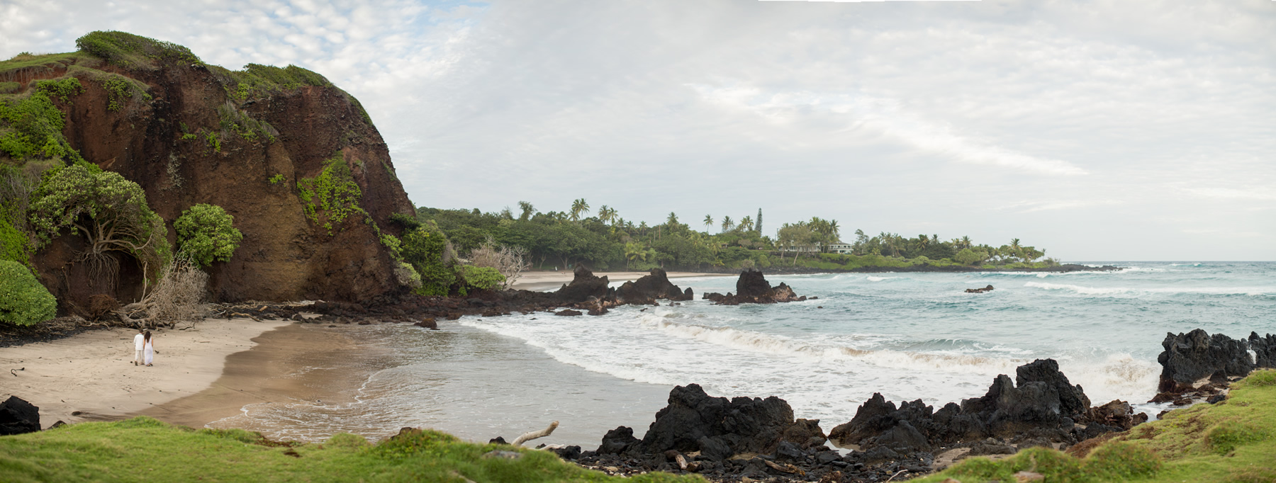 A couple walks along a deserted beach in Hana Maui after their wedding ceremony.