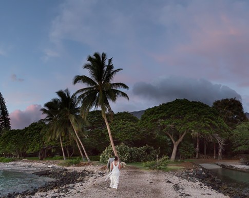 A couple walk into the evening sunset in Maui in a panoramic photo.
