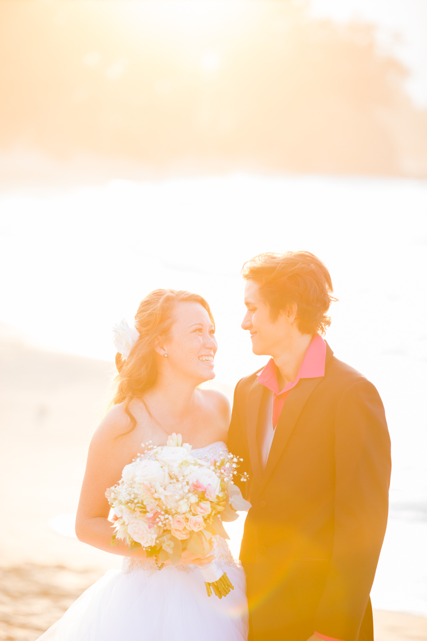 wedding couple laughing with a bright sun behind them