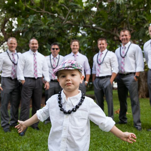 picture of a young boy in newsboy cap spreading his arms in front of groomsmen and groom