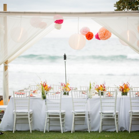 a tropical wedding table set against the ocean with bamboo awning