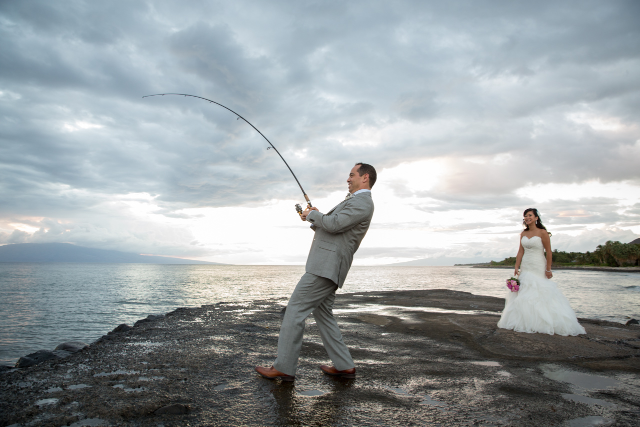 a groom pretends to be catching a fish on the pier near lahaina maui