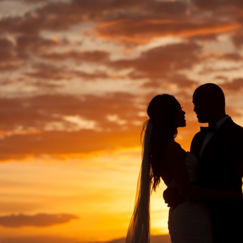 a photograph of a wedding couple sillhouetted against a maui sunset