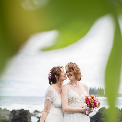 2 same sex brides in love framed between leaves