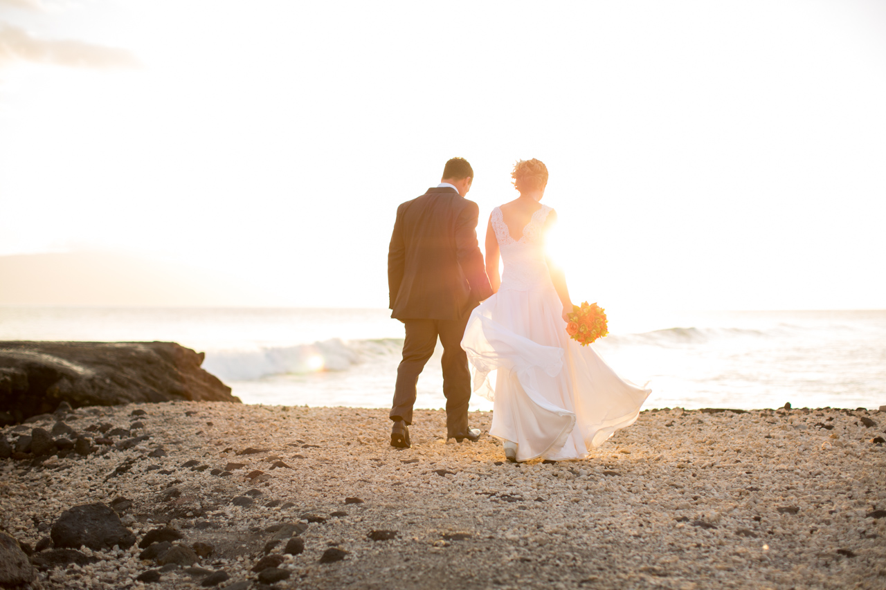 a picture of a bride and groom walking towards the sea at sunset in maui
