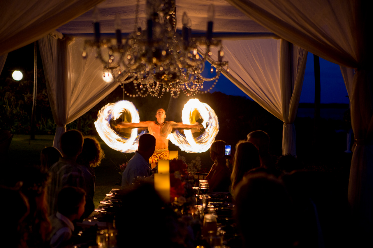 a photograph of a hawaiian fire dancer while wedding guests look on in makena maui