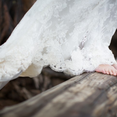 Photography of a bride in Maui at her wedding, barefoot on driftwood.