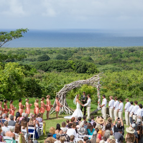 wedding scene in hana maui with arch and rain squall in distance
