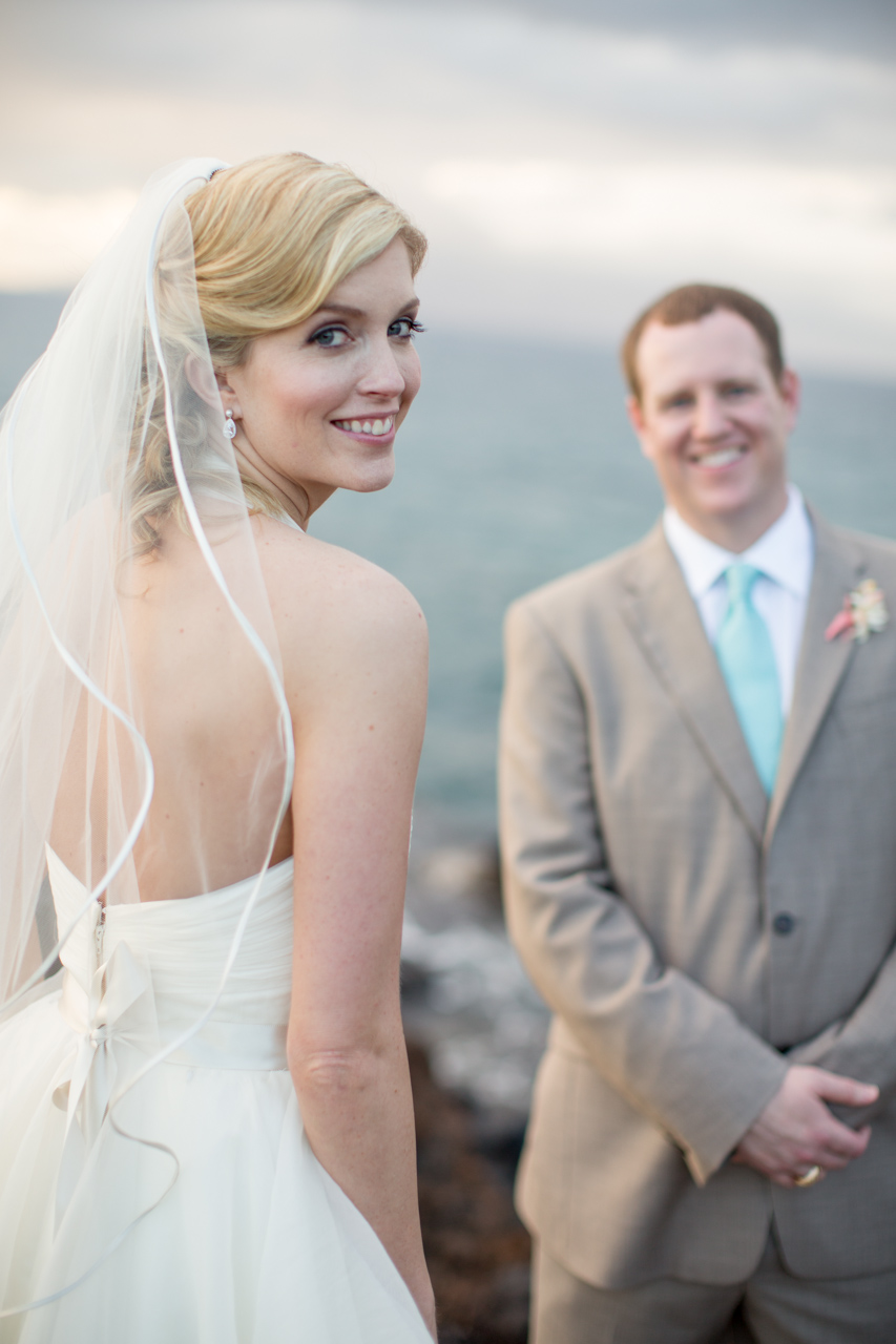 Image of a bride with her groom looking on behind her