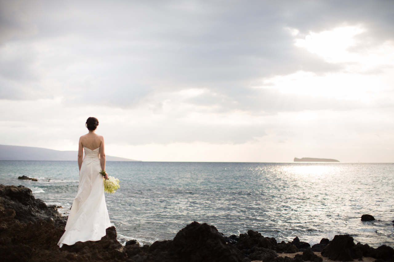 photograph of a bride standing on a lava rock coast looking out at molokini lookout.