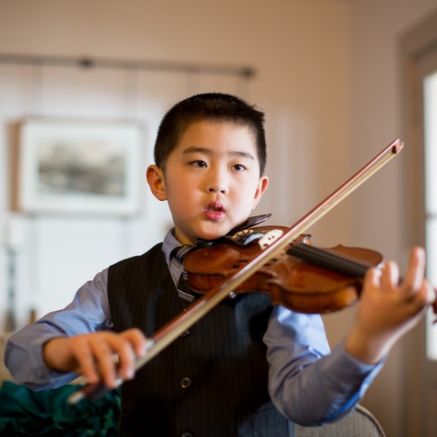 Picture of a young boy practicing his violin for a performance during a wedding ceremony.