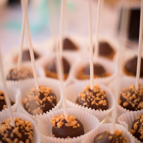 Chocolate covered desert cake pops sprinkled with roasted nuts