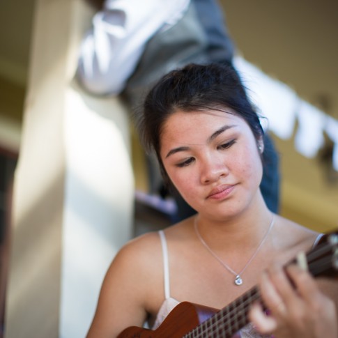 Wedding guest strums her ukulele as the ring bearer glances down at her.