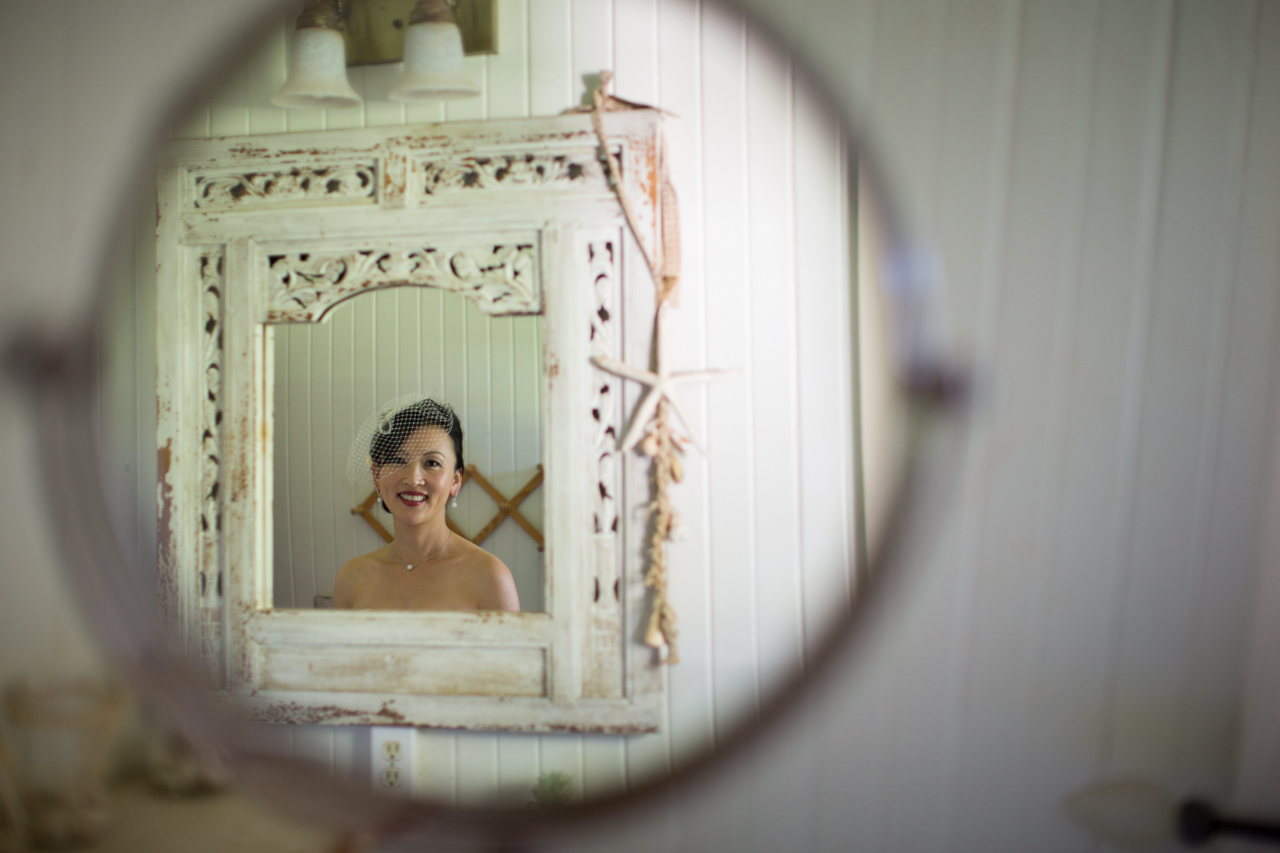 Bride smiles as she glances at her reflection before making her grand entrance at the olowalu plantation house on Maui