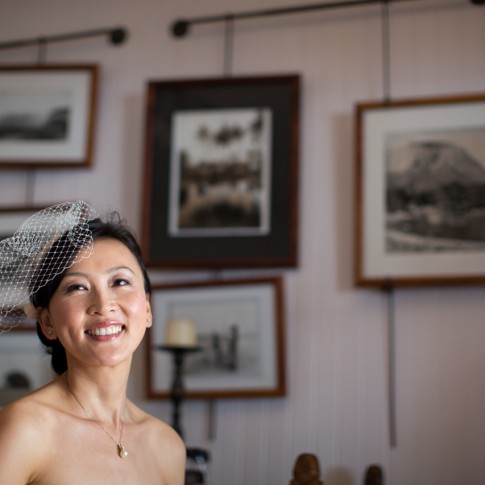 Bride smiles with a vintage birdcage veil at the olowalu plantation house on Maui