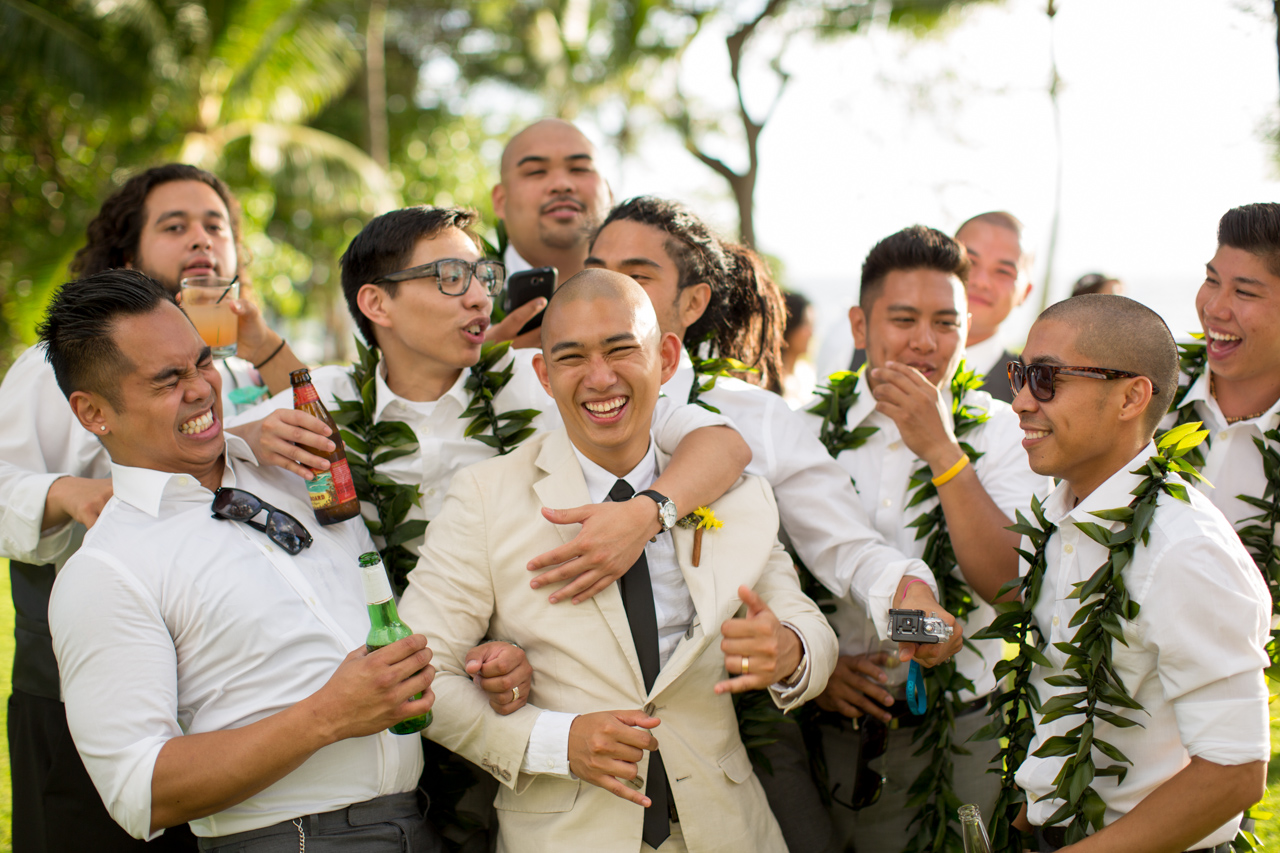 groomsmen cheering on groom in suits with beer and leis and sunglasses